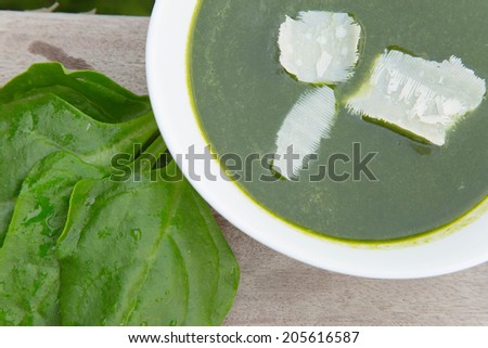 Fresh spinach leaves and a plate of spinach cream soup
