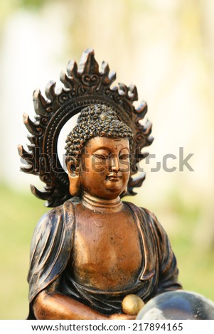 Copper like mini sculpture of Buddha in the garden