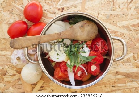 Prepared food ingredients for cooking Italian tomato sauce - salsa. Ingredients are placed in the pot which is on the wooden surface