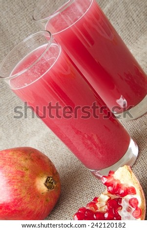Healthy vitamin beverage: fresh made pomegranate juice. Pomegranate in the background
