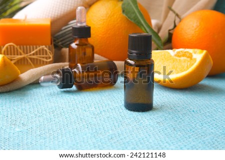 A dropper bottle of sweet orange essential oil. Oranges in the background