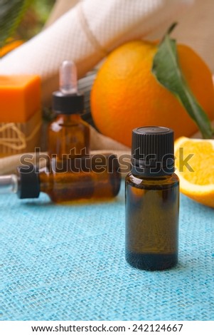 A dropper bottle of sweet orange essential oil. Oranges in the background