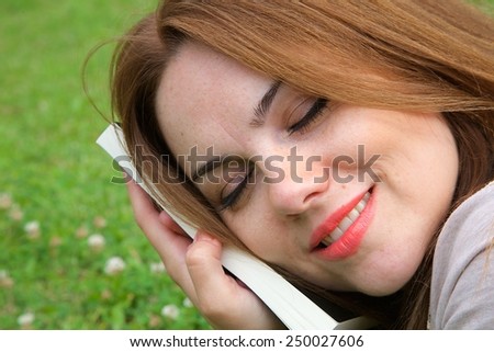 Young pretty woman in her early thirty  put the read book close to her face. Green background