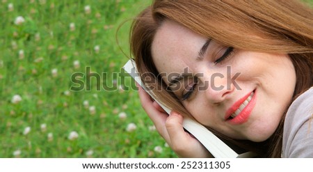 Young pretty woman in her early thirty  put the read book close to her face. Green background