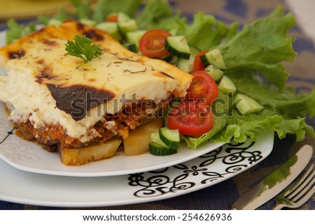 Traditional Greek dish with minced meat - moussaka. Served with fresh vegetables.