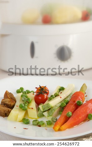 Vegetarian low-calorie lunch: steamed vegetables and croutons. Steamer in the background