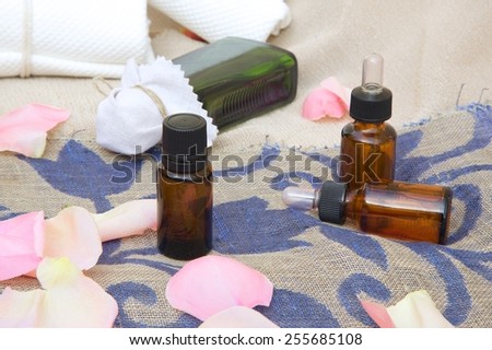 A dropper bottle of rose essential oil. Rose petals in the background