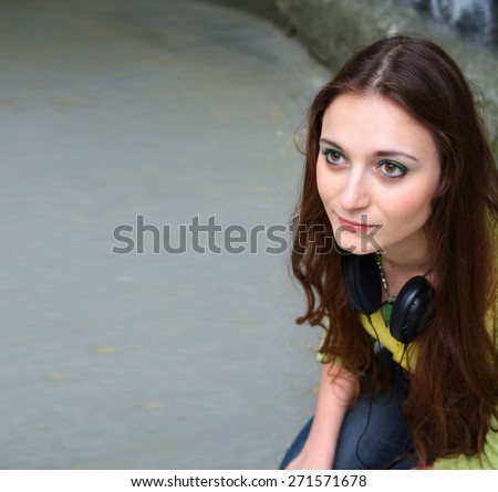 A young girl with headphones hanging at your neck. Free space for a text