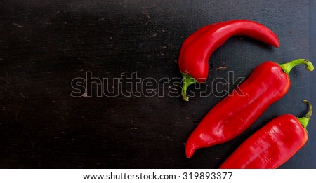 Fresh red hot chill pepper on a black wooden surface. Background. Free space for a text