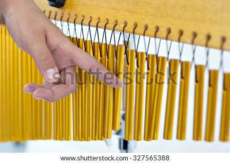 Hand playing one set of bar chimes on white background. Image uses selective focusing and suitable for background purposes only.