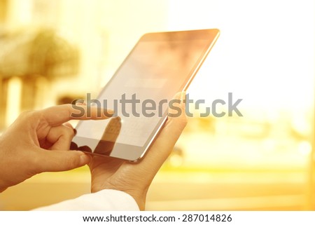 Young woman with digital tablet in the city.A young woman is holding a digital tablet. The image is taken in the city. The face of the young woman is not visible.