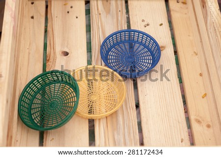 Three plastic basket on the wooden floor.