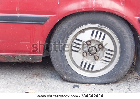 Bangkok, THAILAND - February 6 : flat tire on car wheel in Bangkok, Thailand on February 6, 2012.The old red car flat tire on the road