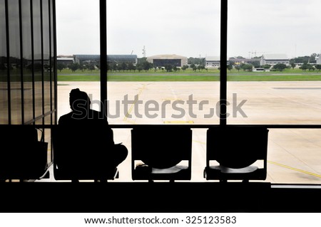 A silhouette of a woman sitting on a chair at the airport