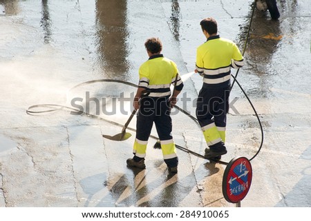 utility service company men workers cleaning the street with water pressure at city