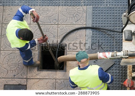 utilities workers moves the manhole cover to cleaning the sewer line for clogs
