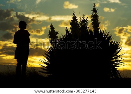 woman on beach dunes with flowers at sunset silhouette