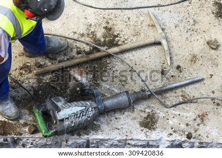 construction worker with pneumatic hammer drill , electric grinder and pick  to repair  water and sewer pipes