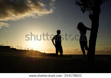 woman balancing in slack line , slacklining , and man looks at him  at sunset