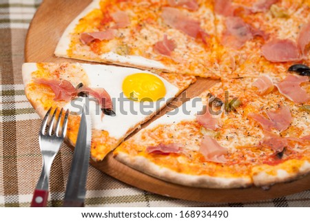 delicious slice of pizza with egg on wooden plate