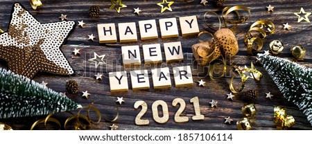 Photo of Banner.Happy New Year 2021. A symbol from the number 2021 with Golden balls, stars, sequins and a beautiful bokeh on a wooden background. The concept of the celebration.