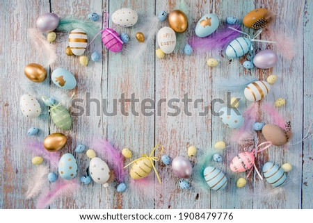 Banner. Easter frame with eggs and feathers on a blue wooden background. The minimal concept. Top view. Card with a copy of the place for the text.