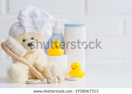 Baby bath accessories, children care, a yellow bear with a towel on its head, a brush and bottles of shampoo. 商業照片 © 