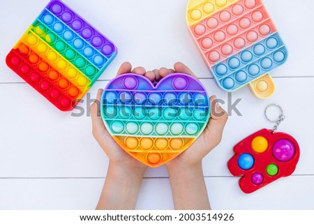 A child with a colorful game "Pop it". Anti-stress. Close-up of children's hands playing with the popular pop It fidget toy. Autism.