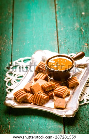 caramel candies and caramel sauce on wooden table.Vintage filter.