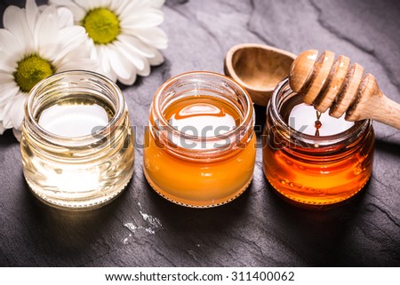 Honey in jar with honey dipper on black stone background