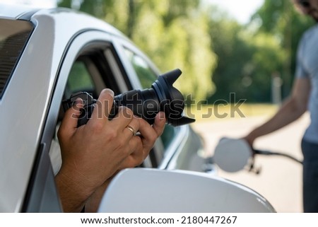 A paparazzi sits in his car and takes pictures of a famous person.  Spy with camera in the car. A private detective, sitting inside the car, taking pictures with the camera. Foto stock © 