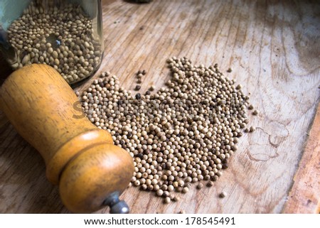 Pepper mill and pepper on wooden background