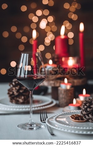 Rustic table decor for Christmas or New Year family dinner. Centrepiece with red candle, dry orange, cone, cinnamon, anise. Zero waste eco-friendly home. Cozy atmosphere, dark background. Close up Foto d'archivio © 