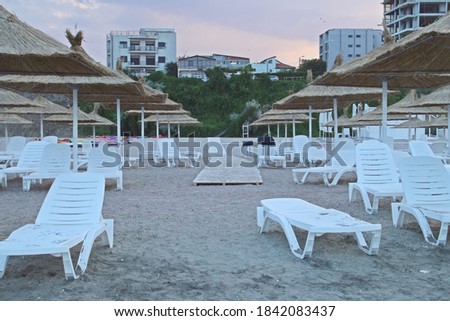 Umbrellas and deck chairs on a lonely beach at sunset. Beach three slippers (Romanian; Plaja trei papuci) in Constanta, Romania. Imagine de stoc © 