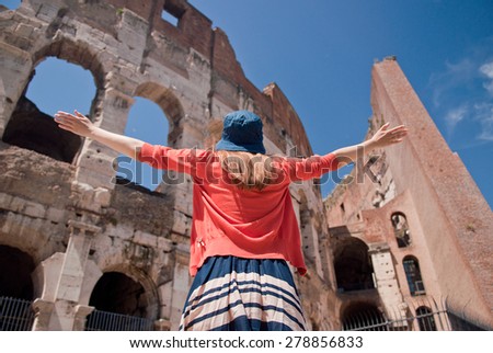 Happy young travel woman in summer hat  by Colosseum, Rome, Italy with arms raised out and up