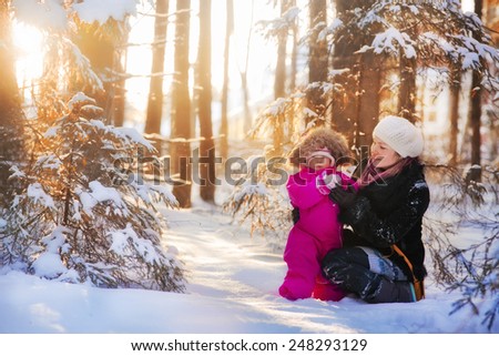 Portrait of mother and baby in sunny winter forest
