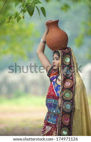 GUJARAT, INDIA - NOVEMBER 30: Unidentified Indian women in colorful traditional dress carry water in clay pots on November 30, 2011 in Gujarat, India