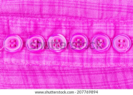 Purple button on scott fabric texture. Button of violet apparel background.