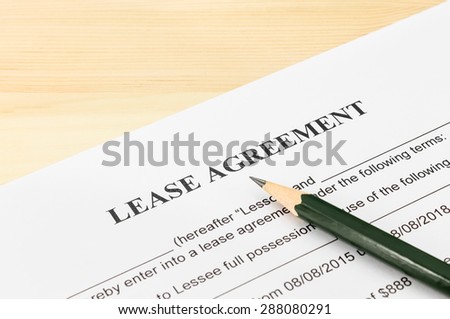 Lease agreement contract sheet and brown pencil at bottom right corner on wood table background
