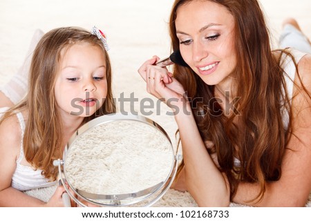 Happy woman and preschool girl looking into mirror