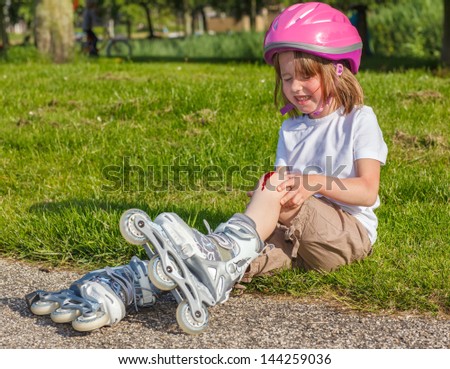 Girl with helmet on but without protective knee pads crying