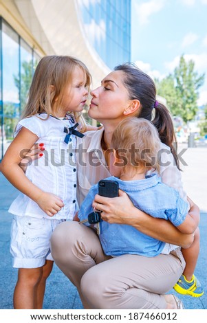 Business mom kissing her children