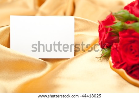 Red roses and blank invitation card on golden satin
