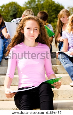 Female student sitting with book in hands, her friends behind