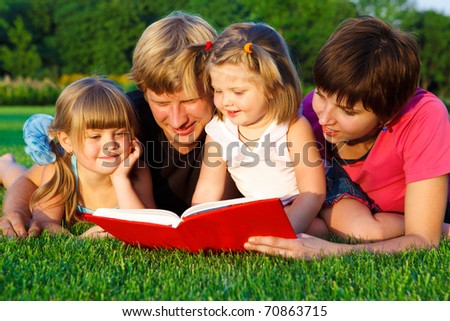 Lovely family reading a book on the  grass