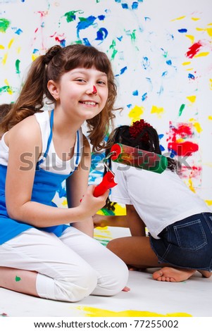 Cheerful junior student holding paint roller in hand