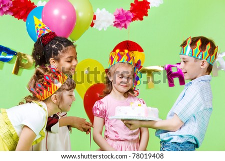 Preschool boy offering birthday cake to his guests