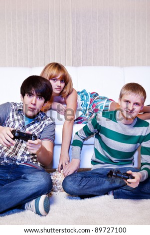 Friends playing computer game and eating popcorn