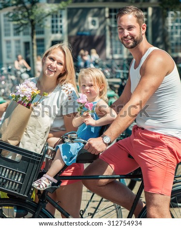 Young smiling family riding bicycles at the streets of Amsterdam