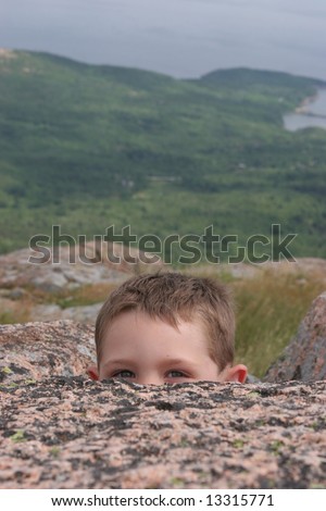 Child peeking over a rock at Acadia National Park